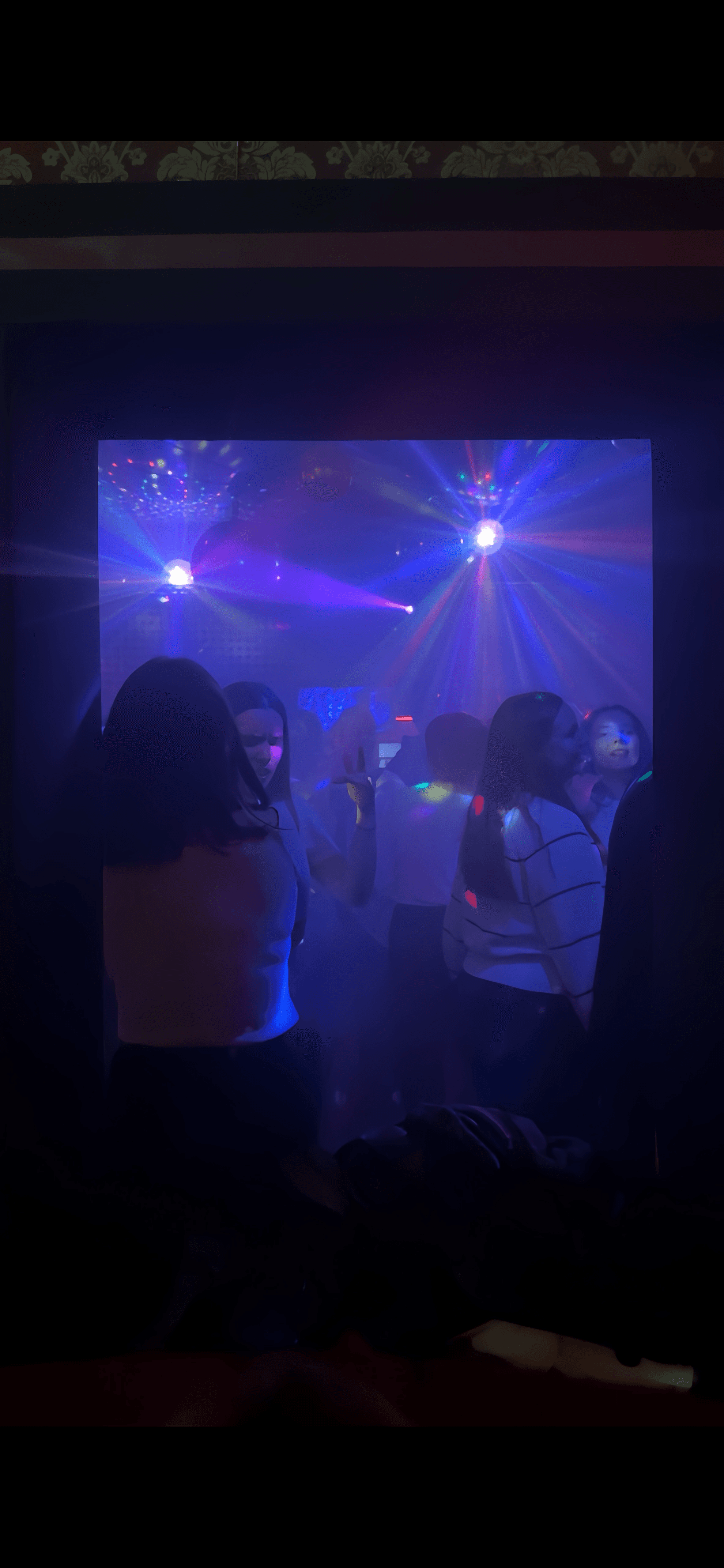 Menschen tanzen in einem dunklen Club unter strahlenden blauen und violetten Discolichtern und Lichteffekten.